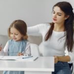 A loving mother helps her daughter with homework at home, fostering a nurturing learning environment.