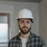 Portrait of a construction worker wearing a hard hat and safety glasses inside a building.